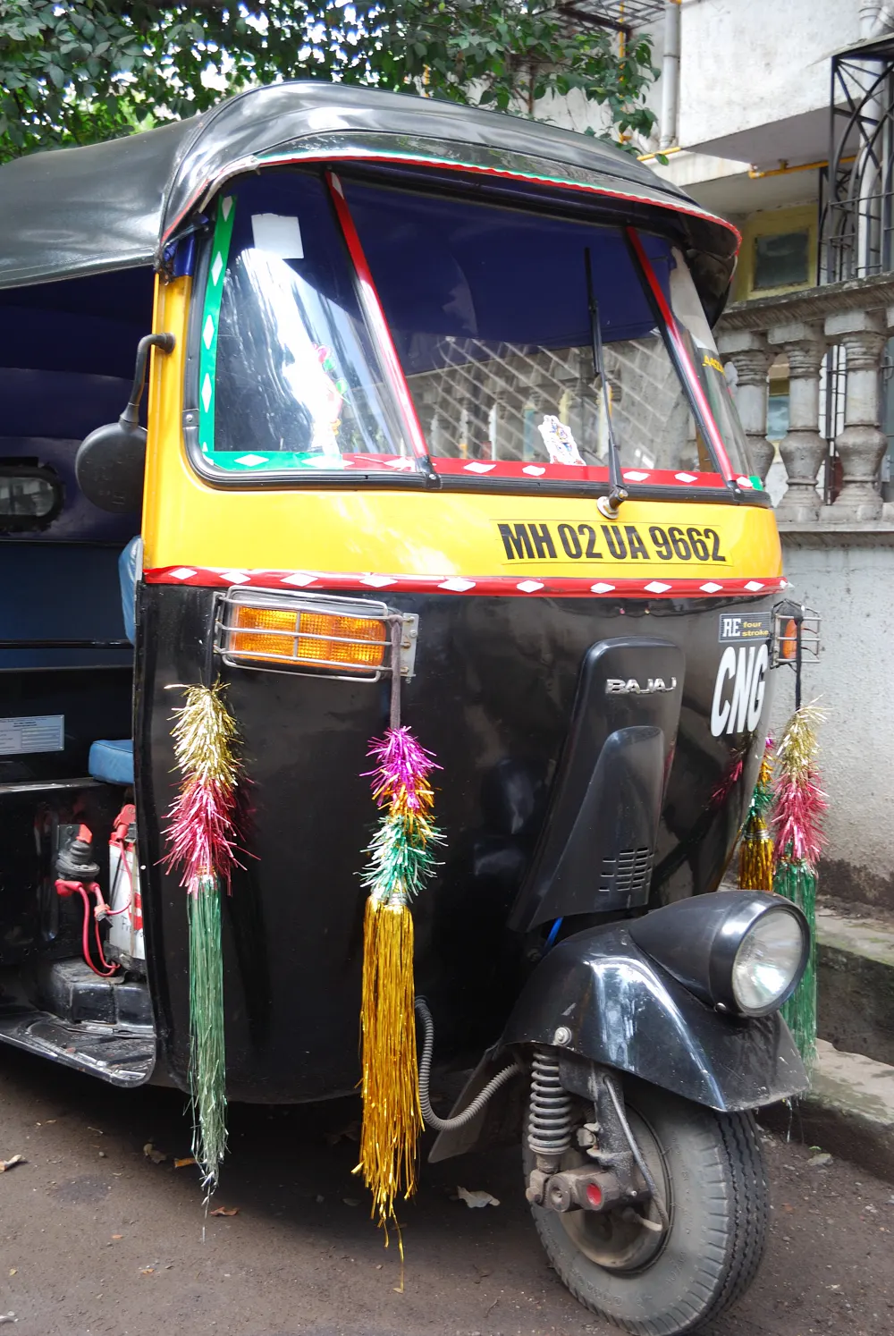 A black and yellow auto-rickshaw parked on a Mumbai street